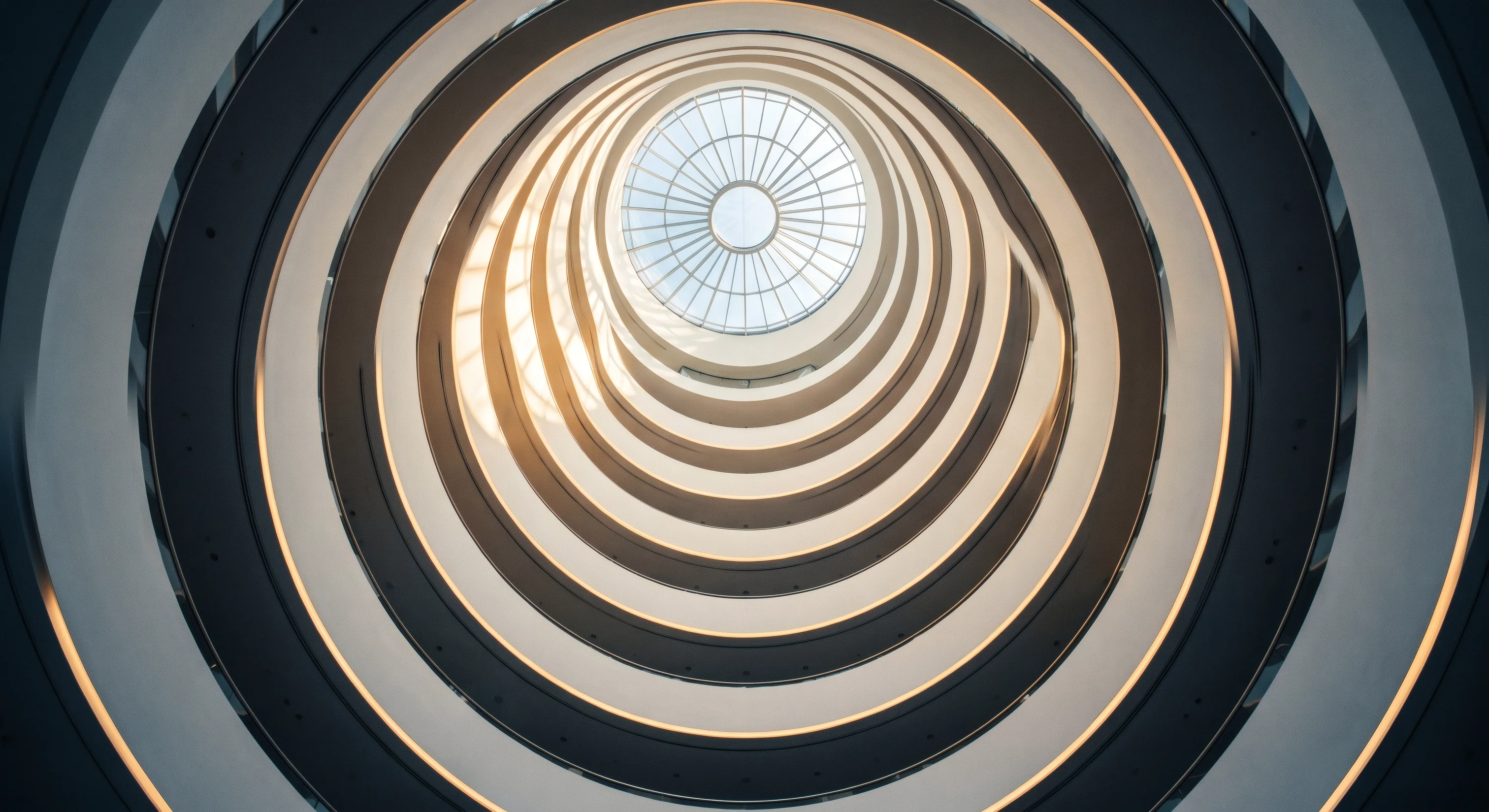 Atrium of a modern building seen from below, balconies spiralling to an oculus